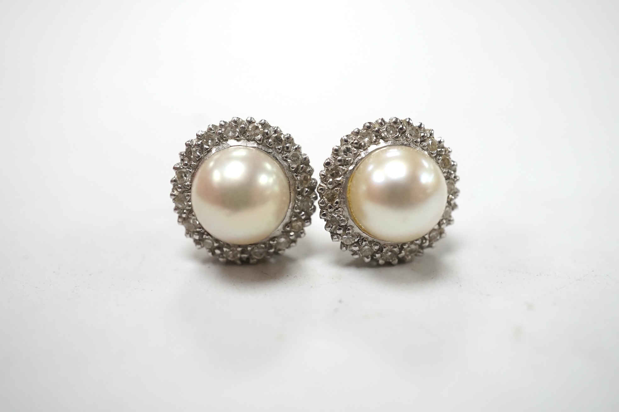 A pair of white metal cultured pearl and diamond cluster set ear studs, 10mm, gross weight 3.6 grams. Condition - fair to good